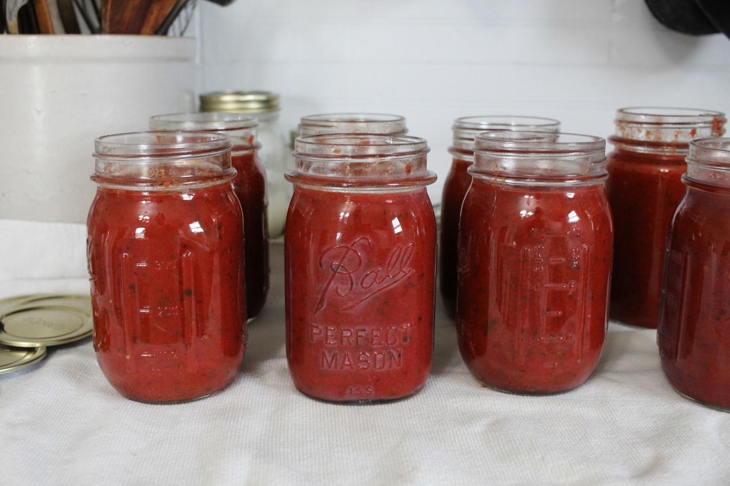 Pizza sauce in jars sitting on a white towel.