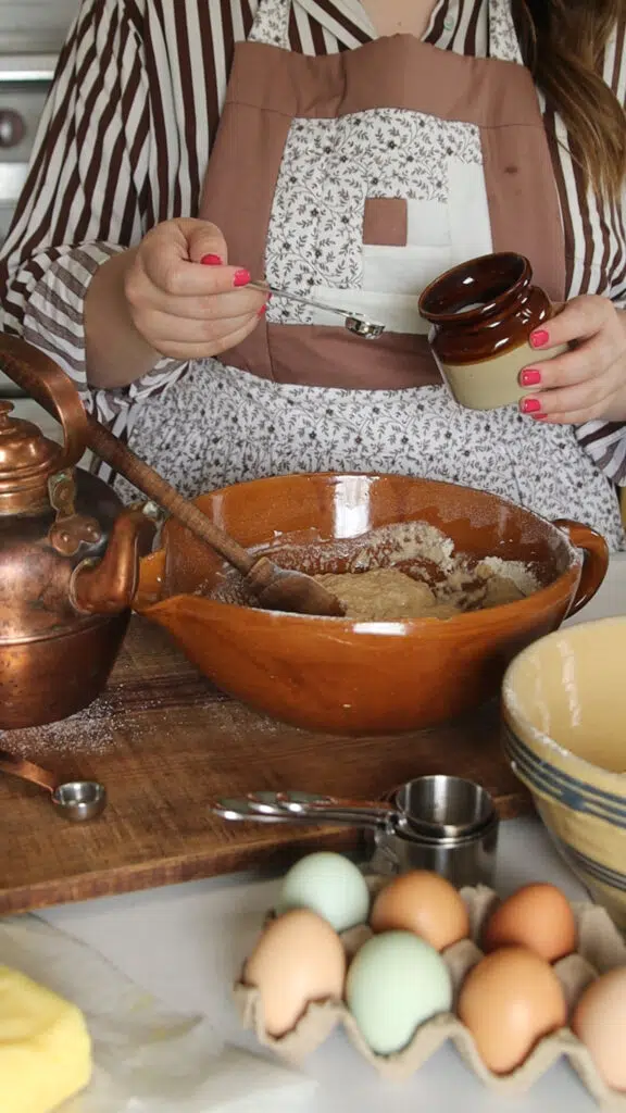 A bowl of batter on a wood cutting board and a crock bowl.